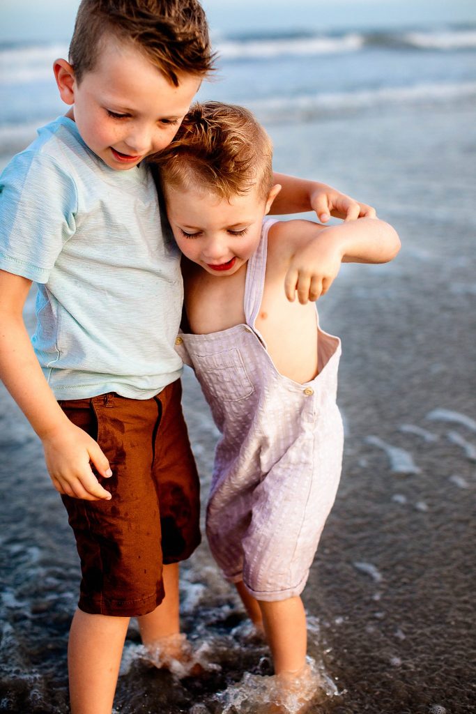 Two toddler brothers hugging in the ocean