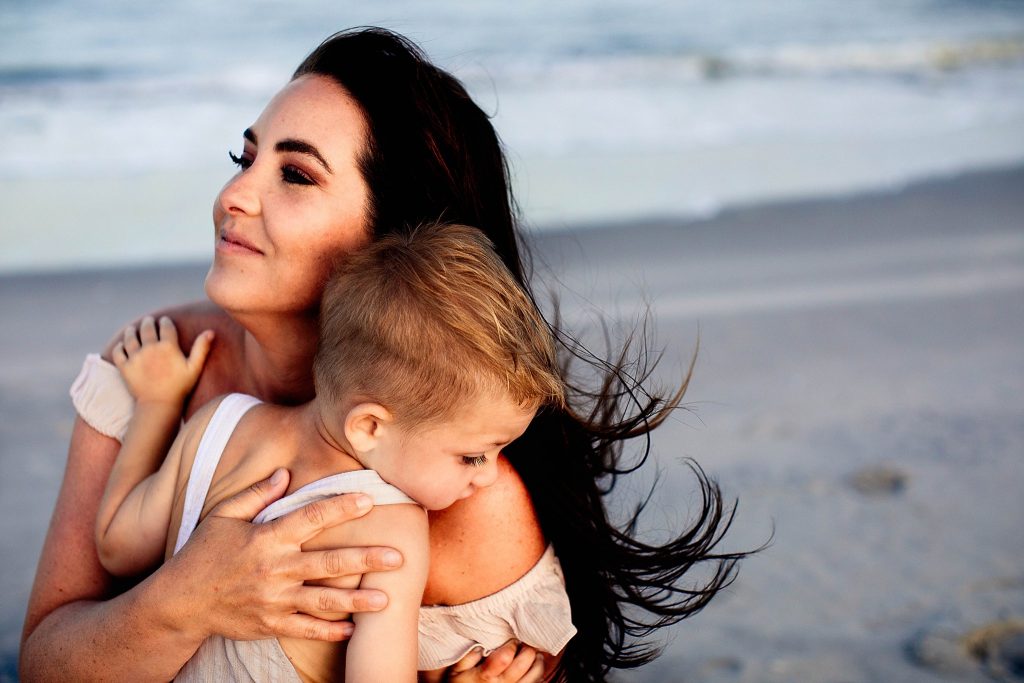 Two year old hugging his mom on the beach