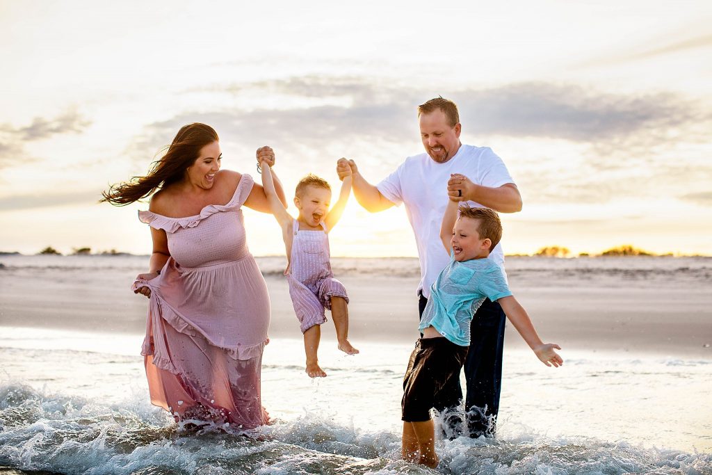 Parents of two young boys swinging them up over the ocean waves