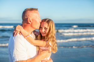 Father kissing his daughters head in front of the ocean in Ocean City New Jersey