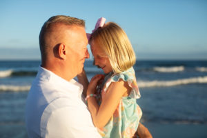 Dad holding daughter on the beach in front of the ocean in Ocean City New Jersey