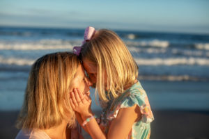 Young girl holding her mom's face touching for head for head on the beach in Ocean City New Jersey