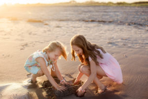 Young sisters playing in the sand at sunset on the beach in Ocean City New Jersey