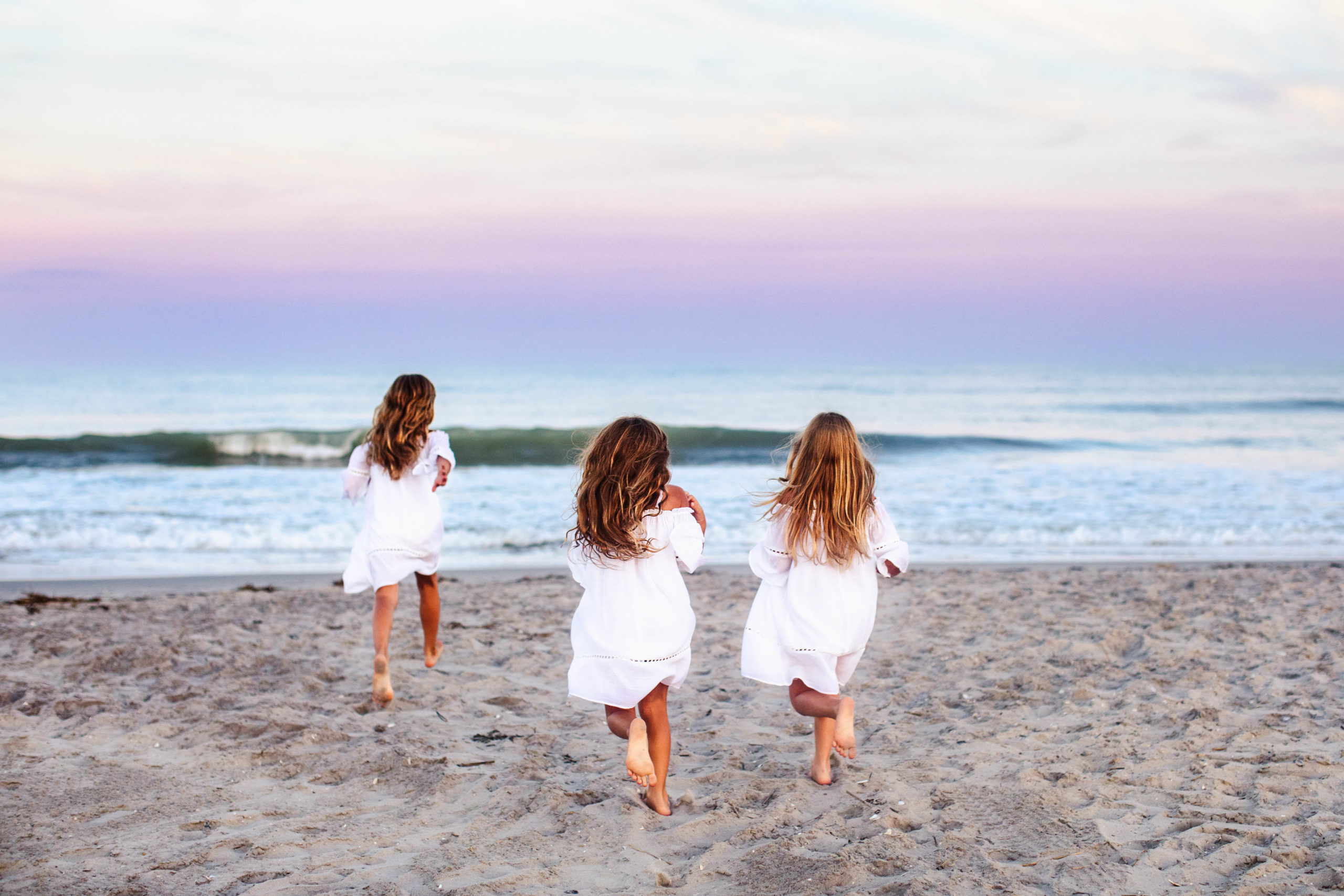 Three young girls running towards the ocean in Ocean City, New Jersey