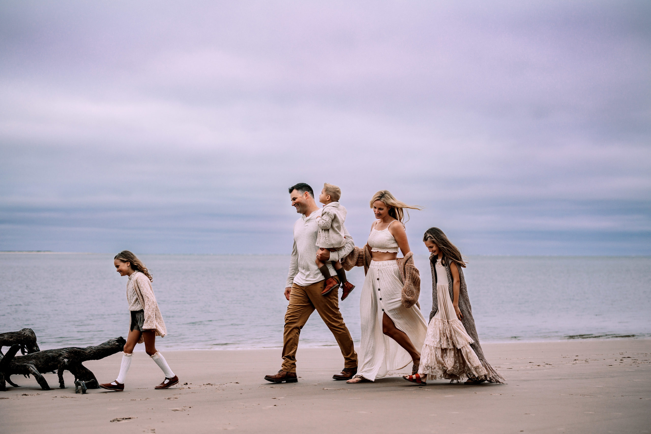 Family of five walking on the beach by the ocean