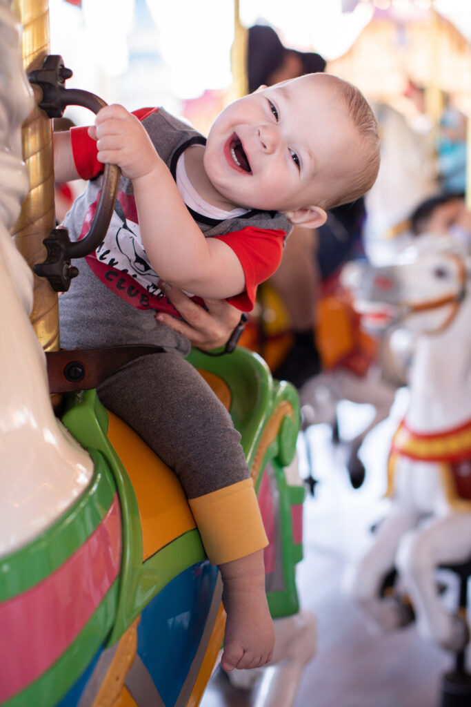 One year old sitting on a Carousel horse in Magic Kingdom at Walt Disney World Florida wearing a Mickey Mouse Rags to Raches Romper